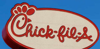 Chick-fil-A restaurant sign illuminated against a blue sky