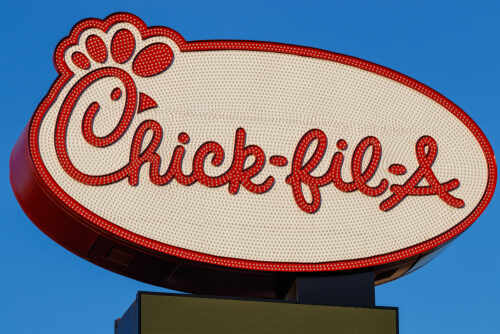 Chick-fil-A restaurant sign illuminated against a blue sky