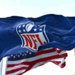 NFL flag waving beside American flag.