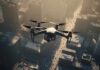 A drone flying over a cityscape during sunset