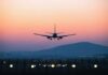 An airplane approaching for landing against a colorful sunset sky