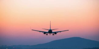 An airplane approaching for landing against a colorful sunset sky