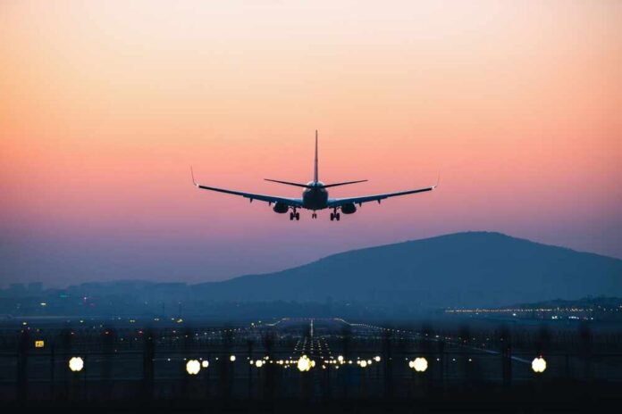 An airplane approaching for landing against a colorful sunset sky