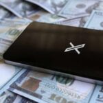 A smartphone placed on a pile of hundred-dollar bills