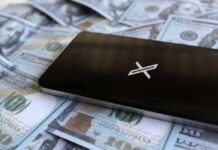 A smartphone placed on a pile of hundred-dollar bills