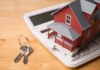 A miniature red house on a calculator with keys nearby