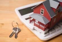 A miniature red house on a calculator with keys nearby