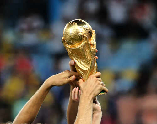 Hands holding the FIFA World Cup trophy aloft in celebration