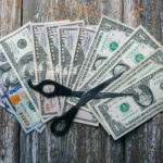 Scissors placed on a spread of various U.S. dollar bills