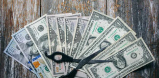 Scissors placed on a spread of various U.S. dollar bills