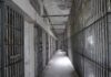 Empty prison corridor with barred cells on either side