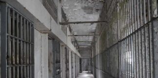 Empty prison corridor with barred cells on either side