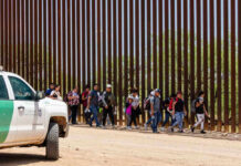 Trump Winning: Record Voluntary Exodus of Illegals Group of people walking by a border fence.