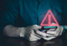 Person holding phone with warning symbol displayed.