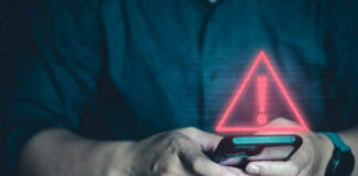 Person holding phone with warning symbol displayed.