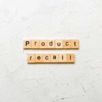 Wooden letter tiles spelling 'Product recall' on a textured surface