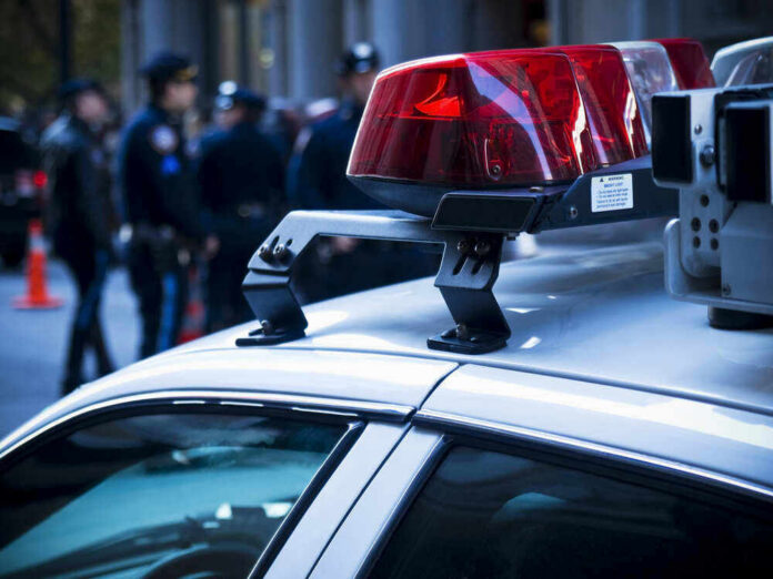 shutterstock_462697451 Police car lights with officers blurred in background.