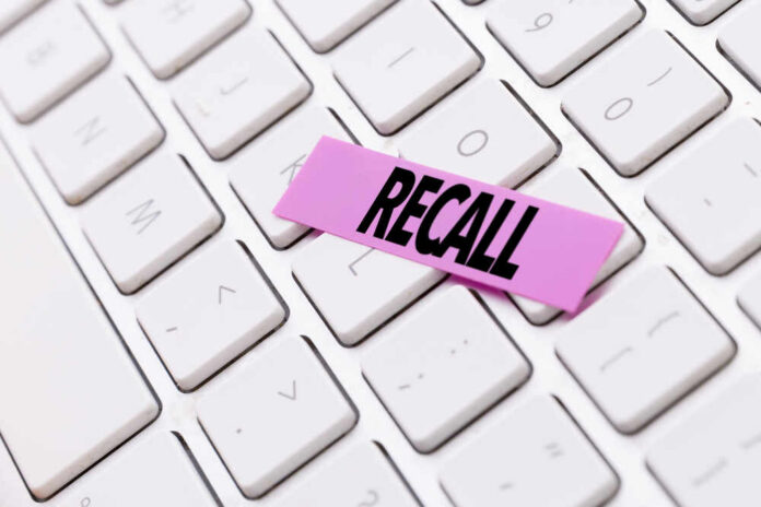 A pink sticky note with the word 'RECALL' placed on a white keyboard