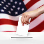 Voting Map UPROAR: Will It Impact You? Hand dropping ballot into box, American flag background.