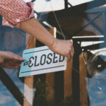 Person flipping closed sign on glass door