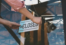 Person flipping closed sign on glass door