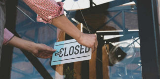 Person flipping closed sign on glass door