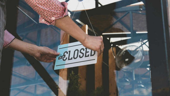 Person flipping closed sign on glass door
