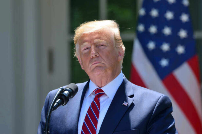 Donald Trump speaking with US flag in the back.