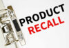 Amputation Risk – Product Recalled A binder clip holding a sheet of paper with the words 'PRODUCT RECALL' printed in bold letters