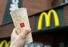 McDonald’s Horror: Attacked With WHAT?! Hand holding McDonalds cup in front of restaurant sign.