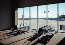 View of an airport waiting area with an airplane taking off in the background