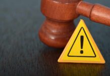 Judge's gavel beside yellow warning triangle sign