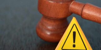 Judge's gavel beside yellow warning triangle sign