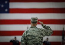Military In Streets? Chicago Teeters A military personnel saluting in front of a large American flag
