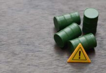 Oil Panic VANISHES — Investors Cheer Four green barrels and a warning sign on a wooden surface