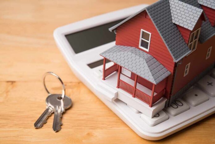 A miniature red house on a calculator with keys nearby