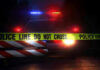7 Dead – Bloodbath Stuns Quiet Town Police car with flashing lights behind caution tape.