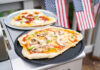 Homemade pizzas on grill trays with vegetable and pepperoni toppings