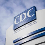 CDC Zeroes In — Taco Bell In Crosshairs CDC building sign against a cloudy sky.