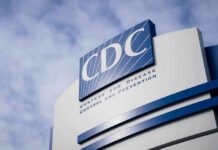 CDC Zeroes In — Taco Bell In Crosshairs CDC building sign against a cloudy sky.