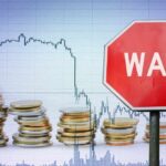 War Shock Slams THESE Farms A stop sign with the word 'WAR' in front of a declining stock market graph and stacks of coins