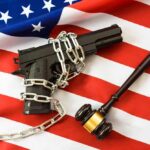 Gun Rights On The Brink A handgun chained on an American flag with a gavel beside it