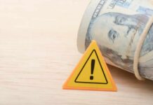 Pentagon Money Bonfire Hits Home A roll of cash next to a warning sign on a wooden surface