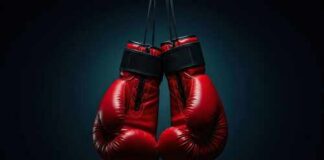 A pair of red boxing gloves hanging against a dark background