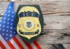 Airport Ambush Stuns Travelers ICE officer badge displayed next to the U.S. flag