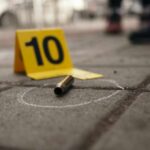 Nine Shooting Scenes, One National Nightmare Bullet casing on the ground next to a numbered evidence marker