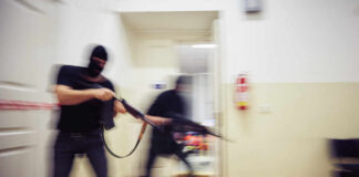 Two masked individuals with guns moving quickly in a hallway