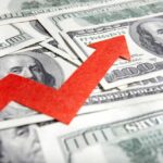 Confidence Craters As Prices Spike A red arrow indicating growth over scattered hundred dollar bills
