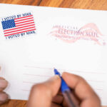 Hands addressing an official election mail envelope