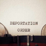 Close-up of a typewriter with the words 'DEPORTATION ORDER' typed on paper
